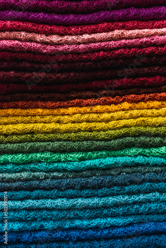 artisan blankets of different colors made by hand from alpaca fiber with ancestral designs and geometric figures in bright colors arranged on a table