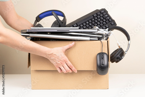 Woman hands holding cardboard box full old used computers, phones, tablets, gadget devices for recycling. Planned obsolescence, e-waste, donation, electronic waste for reuse and recycle concept