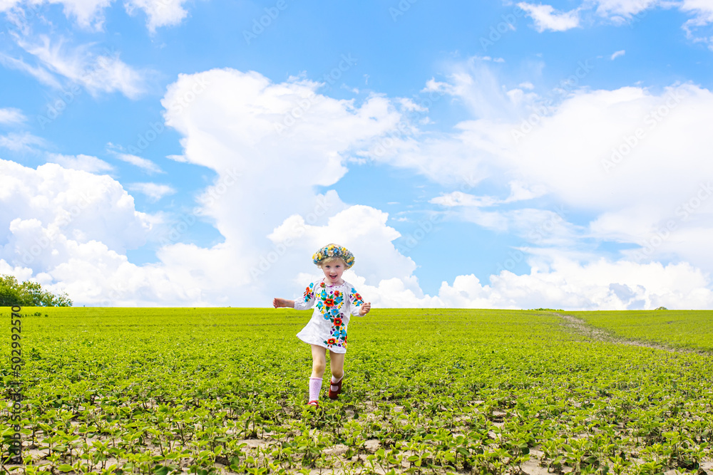 Happy Ukrainian child in free Ukraine without war runs along a rural road in a field of farm soybean.. International Mother Language Day. War in Ukraine Happy Ukrainian child in free Ukraine without war runs along a rural road in a field of farm soybean.. International Mother Language Day. War in Ukraine