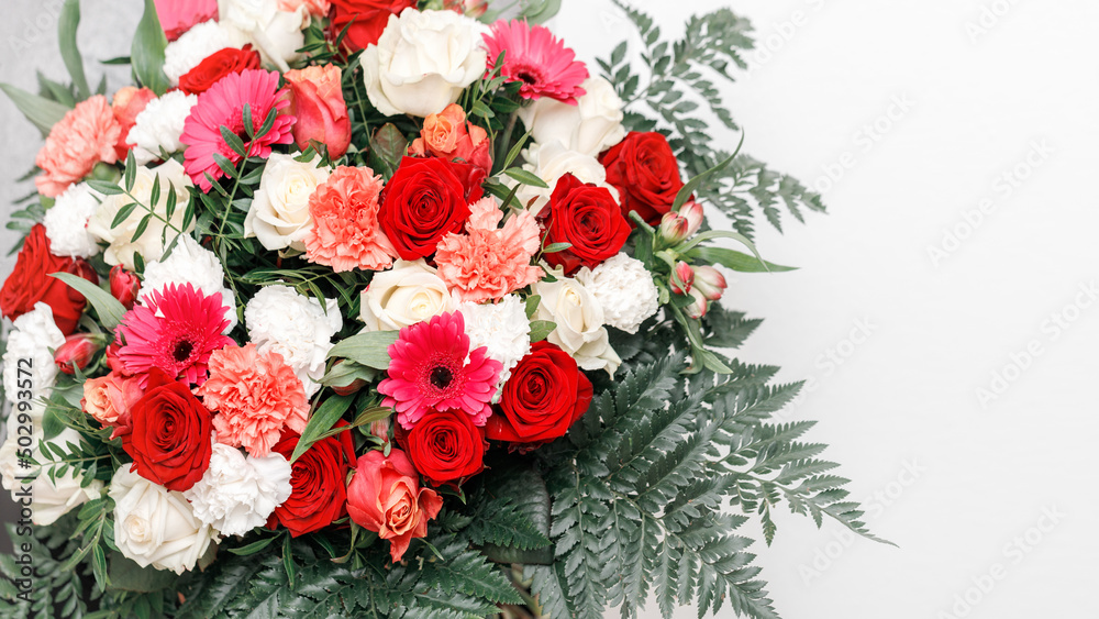 Romantic large bouquet flowers on light background. Red and ivory rose, coral carnation, pink gerbera daisy flowers and fern