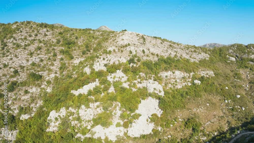 Rock formation. Unique natural landscape.Green bushes and trees grow on the flat gray rock at the top of the cliff. Mount Chelobrdo above Budva. Mountain Cliff Rock tilt reaveal Blue Clear Sky Rock formation. Unique natural landscape.Green bushes and trees grow on the flat gray rock at the top of the cliff. Mount Chelobrdo above Budva. Mountain Cliff Rock tilt reaveal Blue Clear Sky
