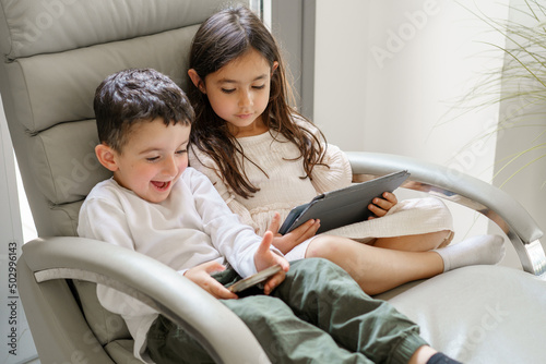Children with tablet computer and mobile phone. Funny little boy playing games on a mobile phone. Girl using laptop pc.