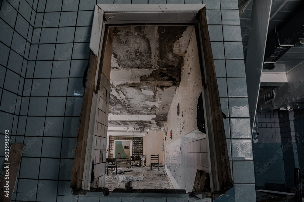 View through a broken window to an abandoned dining room. Shabby and dirty walls. Terrible atmosphere. Broken furniture. View through a broken window to an abandoned dining room. Shabby and dirty walls. Terrible atmosphere. Broken furniture.