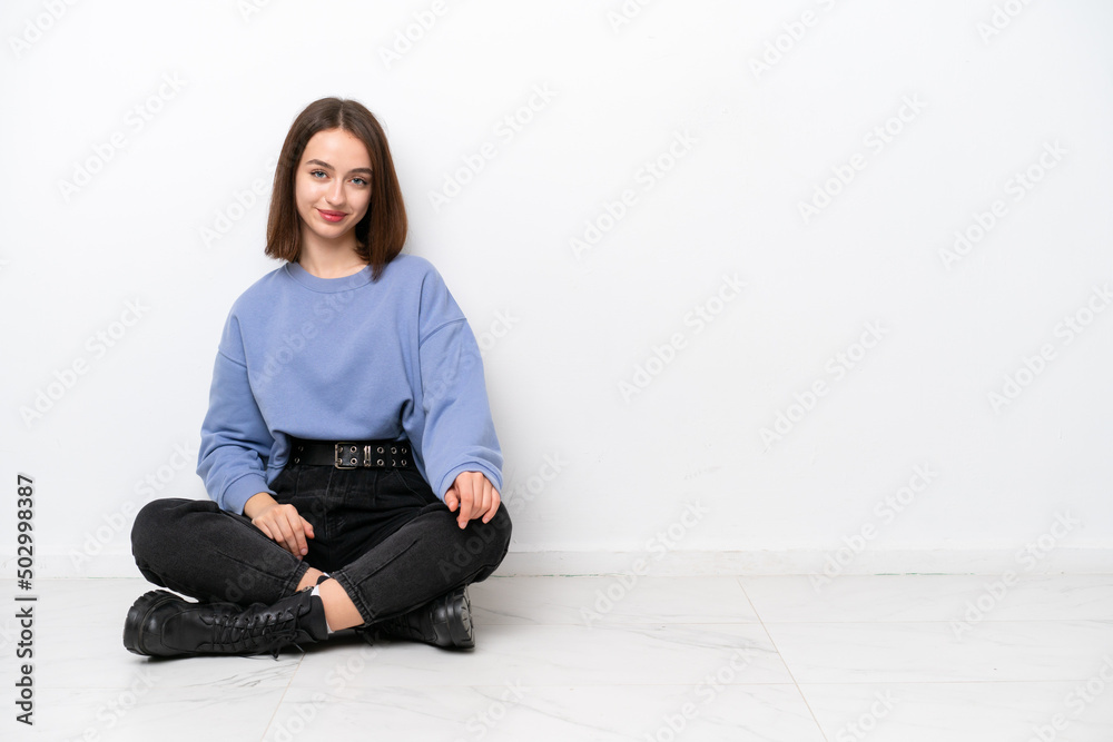 Young Ukrainian woman sitting on the floor isolated on white background laughing Young Ukrainian woman sitting on the floor isolated on white background laughing