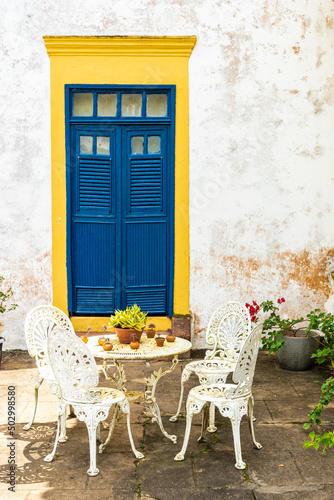 White table and chairs in front of colorful doorstep of old traditional house in Brazil