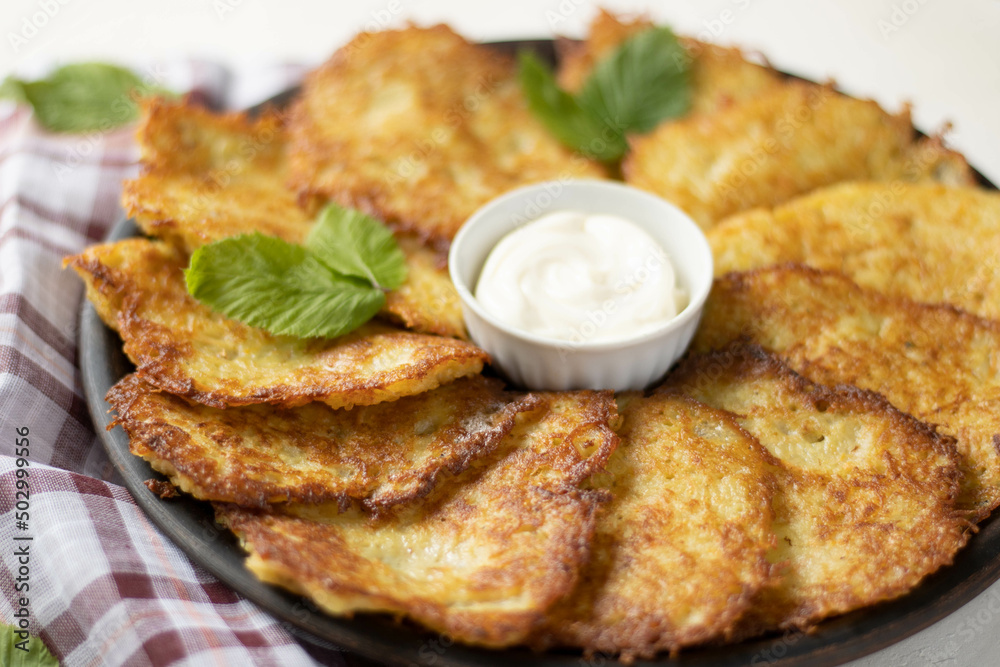 Potato pancakes with garlic and bacon, sour cream on wooden table
Potato pancakes with garlic and bacon, sour cream on wooden table