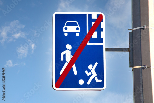 A road sign indicating the end of a residential area, against a blue sky with copy space.
