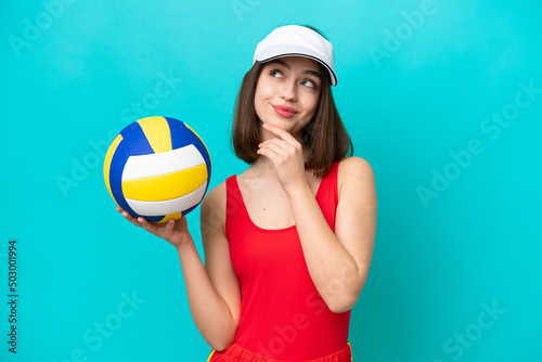 Young Ukrainian woman playing volleyball on a beach isolated on blue background and looking up
