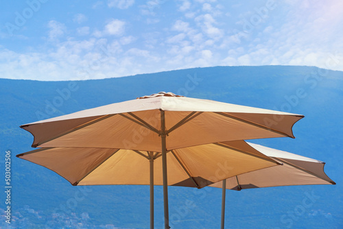 Sun umbrellas against mountains on sunny day.  Montenegro. Vacations concepts © Olga Iljinich