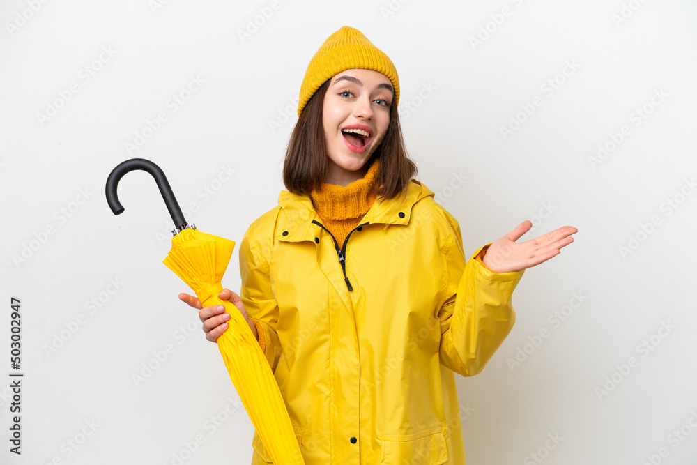 Young Ukrainian woman with rainproof coat and umbrella isolated on white background with shocked facial expression Young Ukrainian woman with rainproof coat and umbrella isolated on white background with shocked facial expression