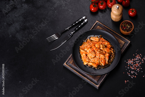Teriyaki chicken with sauce, sesame, herbs and spices on a dark background