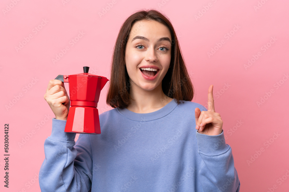 Young Ukrainian woman holding coffee pot isolated on pink background pointing up a great idea Young Ukrainian woman holding coffee pot isolated on pink background pointing up a great idea