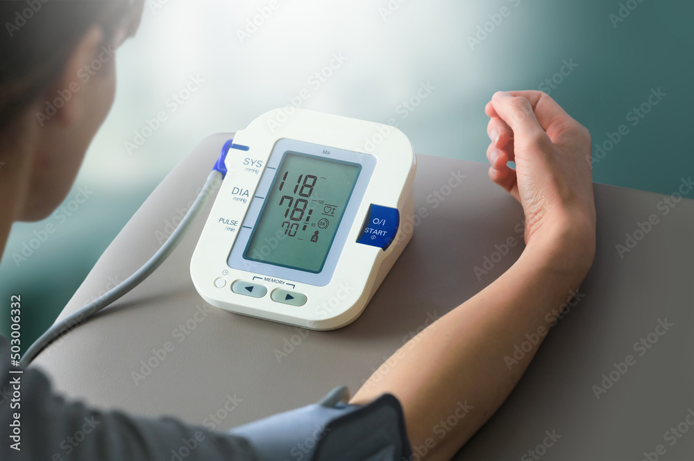 Young woman check blood pressure monitor and heart rate monitor with digital pressure gauge. Health care and Medical concept Young woman check blood pressure monitor and heart rate monitor with digital pressure gauge. Health care and Medical concept