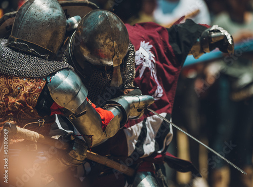 Pitch battle of medieval knights, using metal armor, axes, swords and shields to defend themselves.
