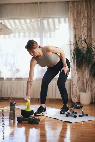 Pretty woman working out at home. Adult lady with beautiful shaped body exercising in the apartment.