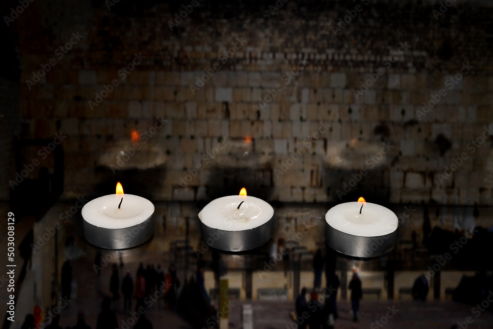 Burning candles on blurred semi transparent Jerusalem Western Wall background. Photo for Israel Memorial Day, Holocaust Remembrance Day or Memorial Day for Fallen Soldiers and Victims of Hostile Acts
