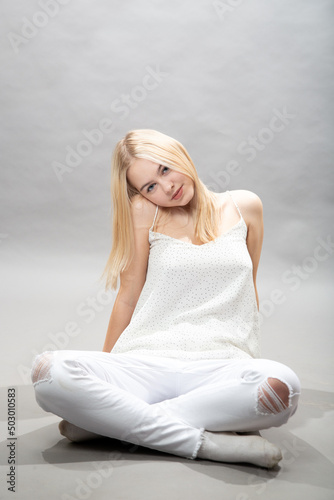 A cute girl in white is sitting relaxed