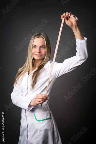 A woman in a white coat holds a measuring tape