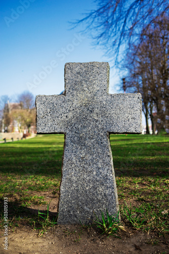 three stone Catholic crosses standing in a row against the background of a cobblestone fence in a park on a sunny day, a sacred burial in a Christian cemetery, monolithic religious monuments