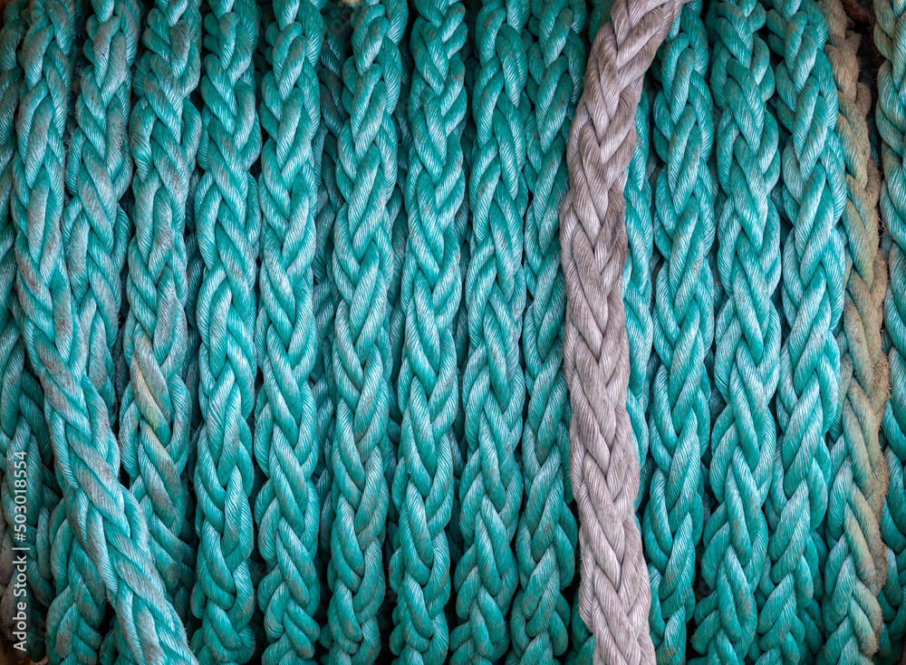 Emerald synthetic ship rope wound on drum close-up. Emerald synthetic ship rope wound on drum close-up.