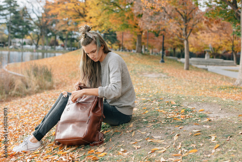 woman wearing neutral colors sitting outside in the fall looking photo