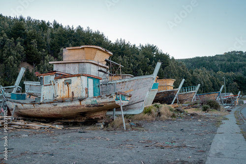 Several boats in the distance, staggered, under construction and abandoned near the beach of Lebu, Chile.