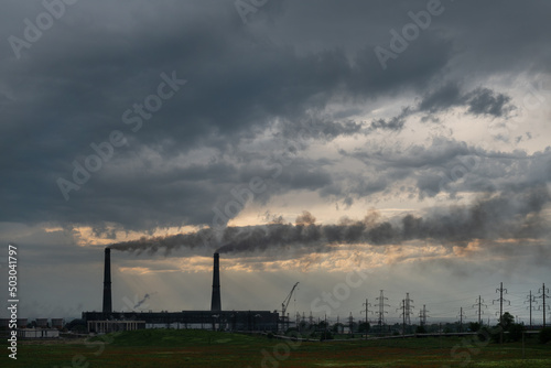 Pipes of coal-fired power plant and poppy field in spring