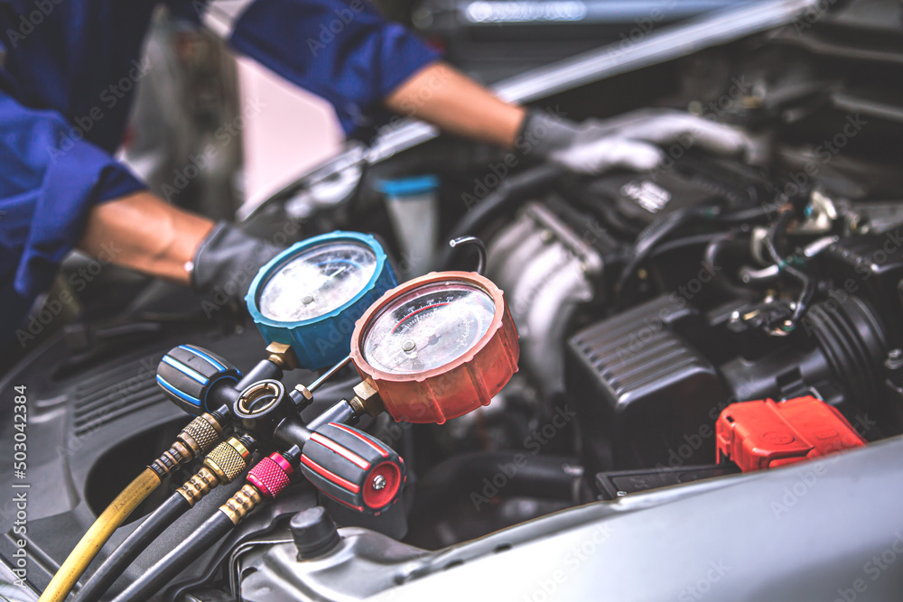 Close up hand of auto mechanic using measuring manifold gauge check the refrigerant and filling car air conditioner for fix and checking for repair service support maintenance and car insurance. Close up hand of auto mechanic using measuring manifold gauge check the refrigerant and filling car air conditioner for fix and checking for repair service support maintenance and car insurance.