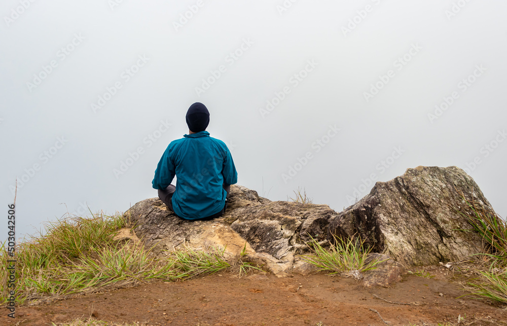 man meditating at mountain rock with white mist background from flat angle