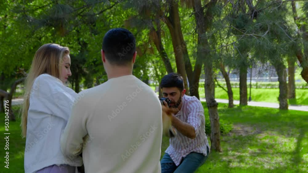 The photographer takes a picture of a young family with a dog in nature. Photo shoot in nature The photographer takes a picture of a young family with a dog in nature. Photo shoot in nature