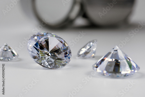 brilliant cut diamond held by tweezers on white background
