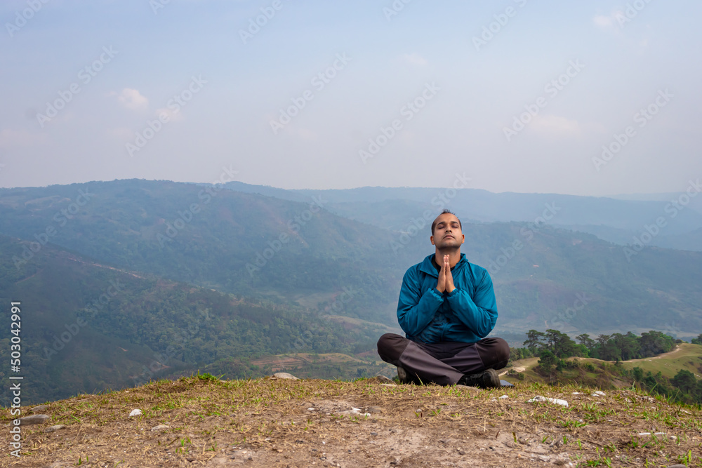 man meditating at hill top with misty mountain rage background from flat angle man meditating at hill top with misty mountain rage background from flat angle