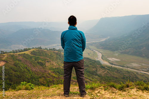 man standing alone at hill top with misty mountain rage background from flat angle