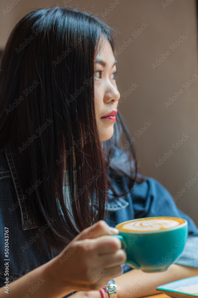 Beautiful fashion asian women hold coffee cup sitting in cafe Beautiful fashion asian women hold coffee cup sitting in cafe