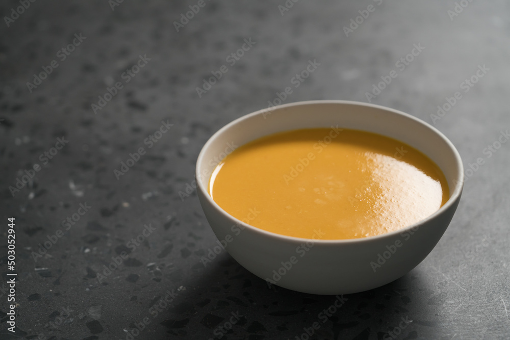 Pumpkin soup in white bowl on concrete background with copy space Pumpkin soup in white bowl on concrete background with copy space