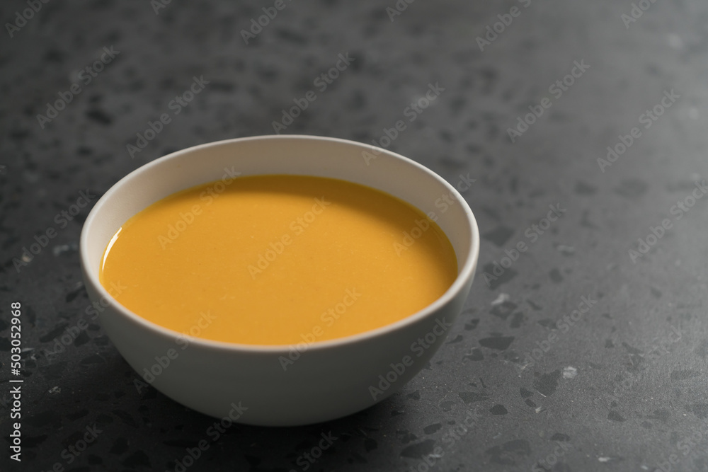 Pumpkin soup in white bowl on concrete background with copy space Pumpkin soup in white bowl on concrete background with copy space