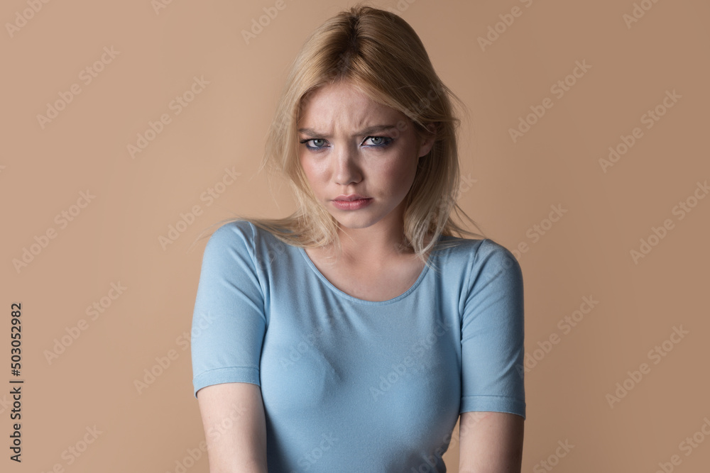 Studio portrait of young angry woman with blue eyes. Sad girl face. Youth and skin care concept. Studio portrait of young angry woman with blue eyes. Sad girl face. Youth and skin care concept.