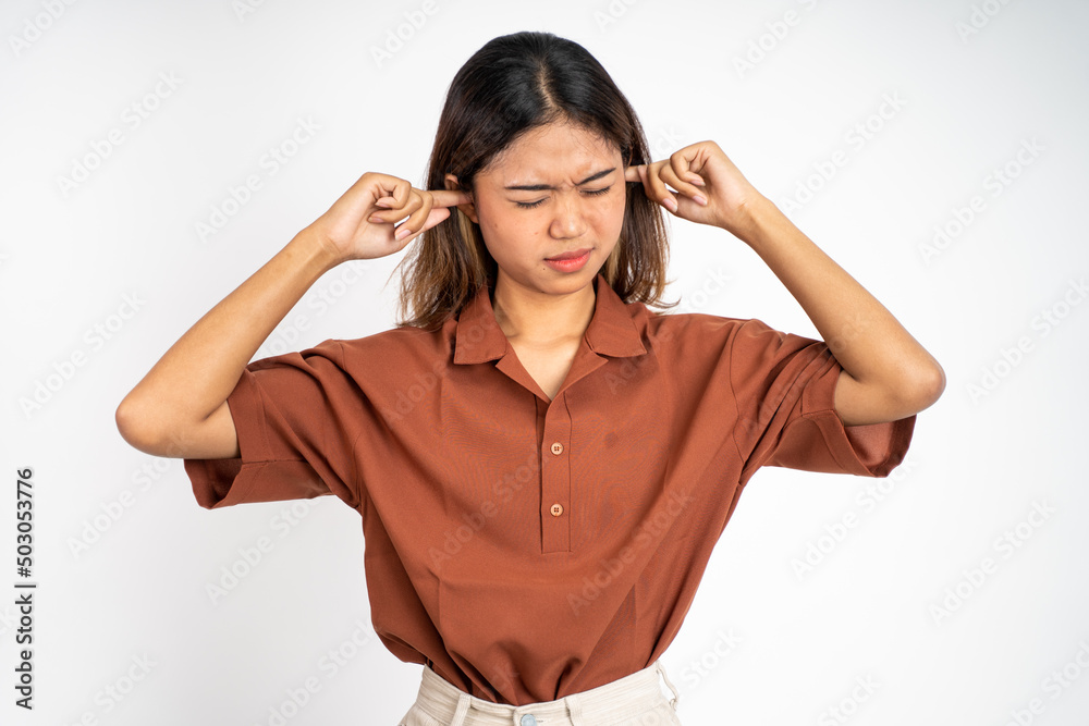 asian woman with annoyed expression covering ears with both hands on isolated background asian woman with annoyed expression covering ears with both hands on isolated background