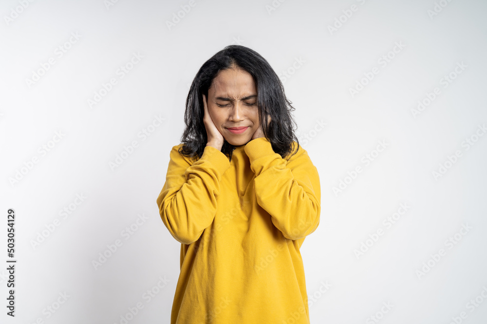 frustrated Asian young woman holding head with headache on isolated orange background