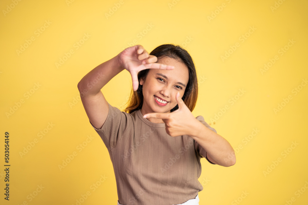 young woman looking at the camera from between fingers forming a frame on isolated background young woman looking at the camera from between fingers forming a frame on isolated background