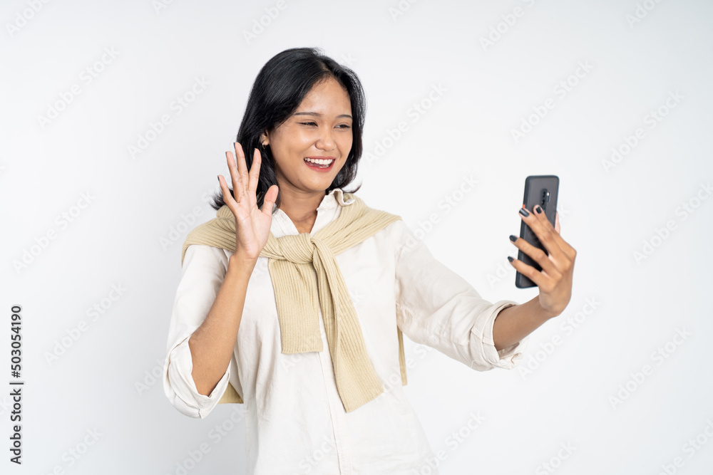 young woman make a video call using mobile phone with saying hello gesture on isolated background young woman make a video call using mobile phone with saying hello gesture on isolated background