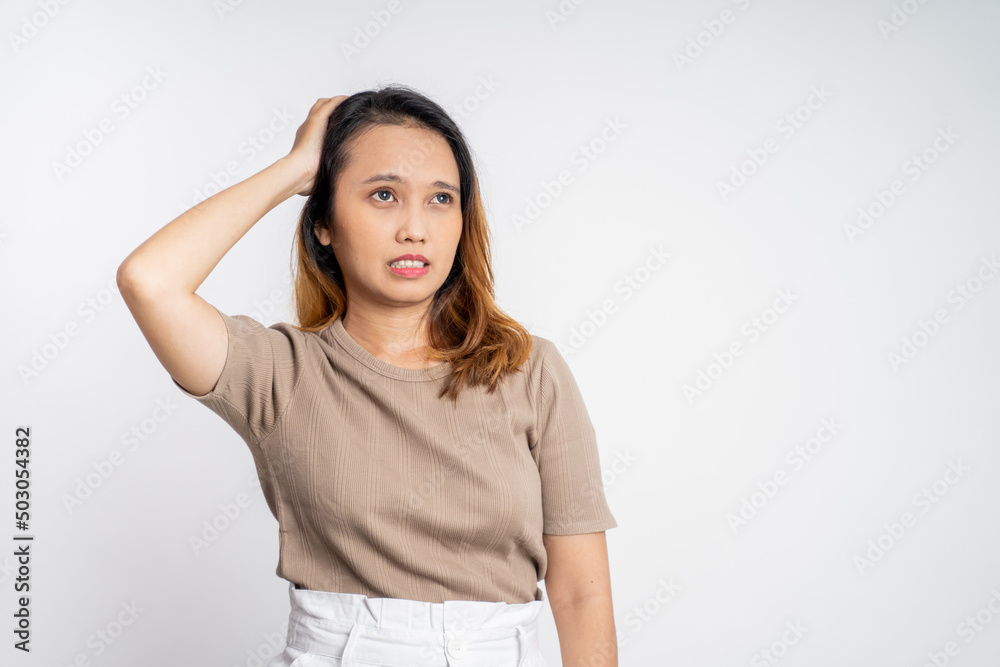 frustrated Asian young woman holding head with headache on isolated orange background frustrated Asian young woman holding head with headache on isolated orange background