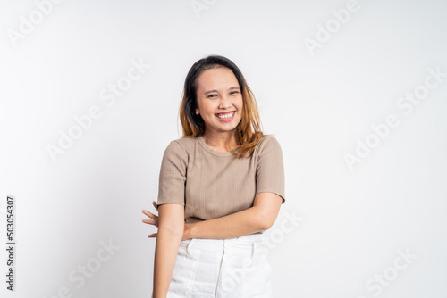 attractive asian ethnicity female looking at camera smiling with crossed arm on isolated background