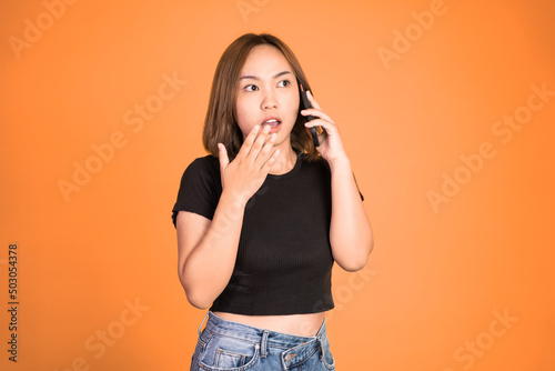 shocked asian woman making a call using a cell phone on isolated background