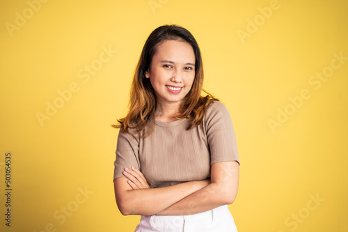 attractive asian ethnicity female looking at camera smiling with crossed arm on isolated background