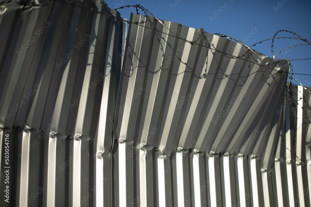 Obraz premium Broken fence. Fence from profile sheet bent. Rumpled iron.