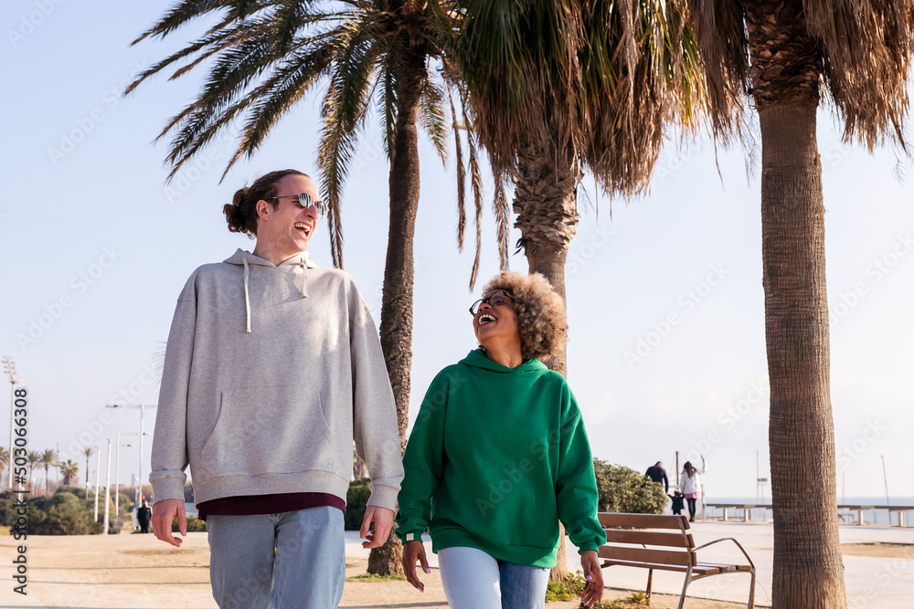 young interracial couple laughing funny while taking a walk, concept of friendship and fun in a relationship young interracial couple laughing funny while taking a walk, concept of friendship and fun in a relationship