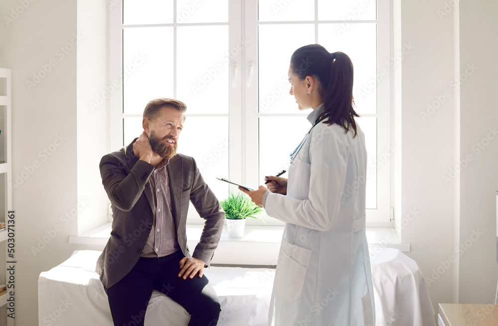 Unwell young man having neck muscular spasm have consultation with doctor in clinic. Female GP consult examine sick male suffering from backache or muscle strain. Inflammation, healthcare concept. Unwell young man having neck muscular spasm have consultation with doctor in clinic. Female GP consult examine sick male suffering from backache or muscle strain. Inflammation, healthcare concept.