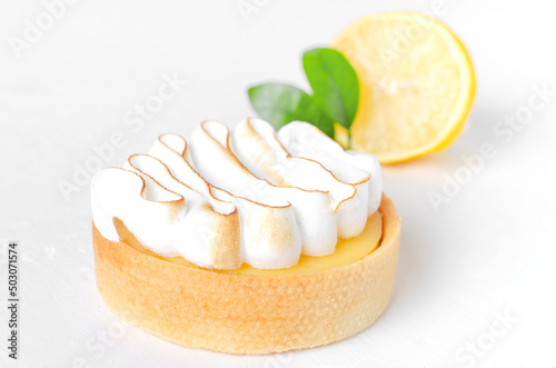 Lemon tart with white cream on white background. Front view