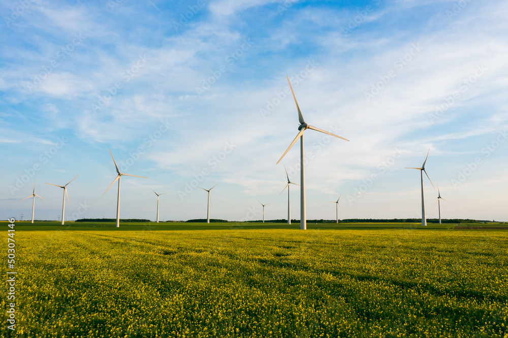 Wind Turbines Windmill Energy Farm. Wind turbines on sunny morning. Windmills wind turbines farm power generators against landscape against blue sky in beautiful nature. Aerial. Wind Turbines Windmill Energy Farm. Wind turbines on sunny morning. Windmills wind turbines farm power generators against landscape against blue sky in beautiful nature. Aerial.